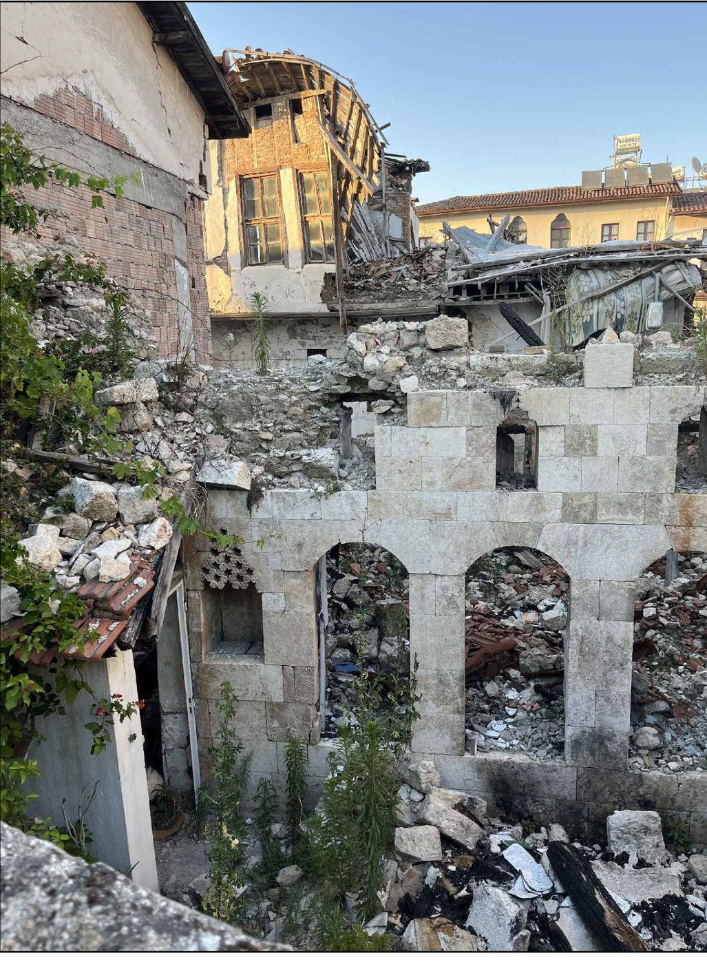 Deprem sonrası mevcut durum — çöken üst kat ve ayakta kalan kemerli cephe